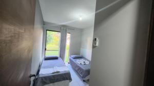 a small room with two beds and a window at Apartamento térreo a 300 metros da praia de Itacimirim com piscina e jardim in Itacimirim +41 photos