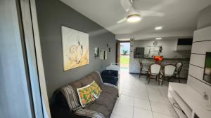 a living room with a couch and a kitchen at Apartamento térreo a 300 metros da praia de Itacimirim com piscina e jardim in Itacimirim