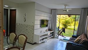 a living room with a tv and a table and chairs at Apartamento térreo a 300 metros da praia de Itacimirim com piscina e jardim in Itacimirim