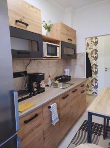 a kitchen with wooden cabinets and a sink and microwave at Lilibella apartman in Miskolc