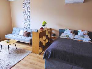 a bedroom with a blue bed and a couch at Lilibella apartman in Miskolc