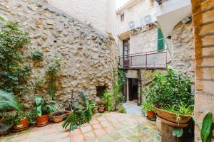 an alley with potted plants and a stone wall at Calvario Townhouse by rentavillamallorca in Pollença