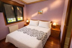 a bedroom with a white bed with two lamps at PENSION LUCERNA in Vigo