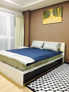 a bedroom with a large bed with a blue blanket at Me Condo by SN in Rayong