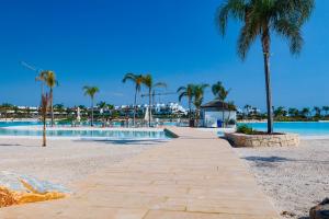 a walkway on a beach with palm trees and a pool at Nieuw Casa Santa Rosalia uitzicht op zwembad in Torre-Pacheco