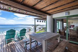a wooden table and chairs on a deck with a view of the ocean at 43 Artemis, Langebaan, 8-sleeper in Langebaan