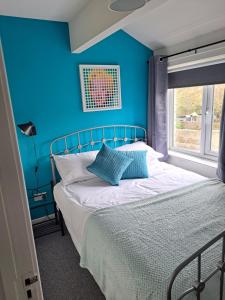 a blue bedroom with a bed with a blue wall at Walkers Court By Treetop Property in Cirencester