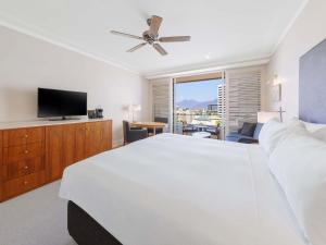 a bedroom with a white bed and a flat screen tv at Pullman Reef Hotel Casino in Cairns