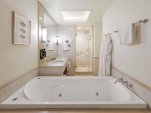 a white bathroom with a large tub and a sink at Pullman Reef Hotel Casino in Cairns