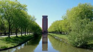 a clock tower in the middle of a river with trees at Van der Valk Hotel Houten Utrecht in Houten