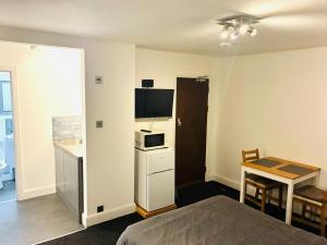 a room with a bed and a table and a microwave at 26 Station Way in Cheam