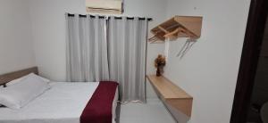 a white bedroom with a bed and a curtain at Casa em condominio com piscina na beira do rio Alegre in Santo Amaro