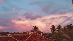 a cloudy sky with palm trees and houses at Cinnamon Shade by Achievers in Negombo