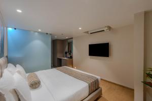 a bedroom with a white bed and a tv at Hotel Shivashish in Ahmedabad