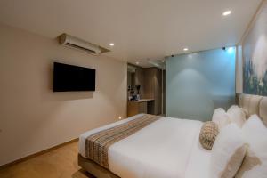 a bedroom with a white bed and a television at Hotel Shivashish in Ahmedabad