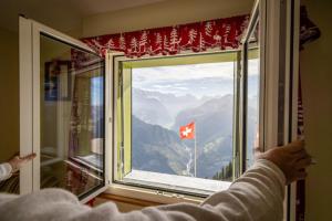 a person looking out of a window with a canadian flag at Hotel Schynige Platte in Wilderswil