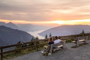 a man and woman sitting on a bench watching the mountains at Hotel Schynige Platte in Wilderswil