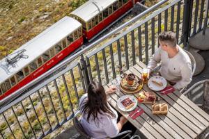 two people sitting at a picnic table with a train at Hotel Schynige Platte in Wilderswil