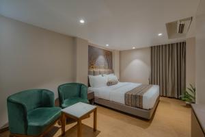 a hotel room with a bed and two green chairs at Hotel Shivashish in Ahmedabad +14 photos