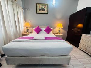 a bedroom with a large bed with pink pillows at Bab Al Bahrain Hotel in Manama