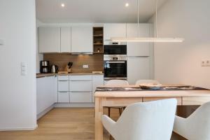a kitchen with a wooden table and white cabinets at Alpenlodge LEO in Mittenwald