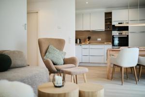 a living room with a couch and chairs and a kitchen at Alpenlodge LEO in Mittenwald