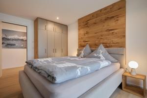 a bedroom with a large bed with a wooden wall at Alpenlodge LEO in Mittenwald +16 photos
