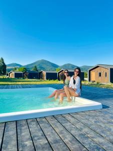 two women sitting on a board in a swimming pool at Красник Хілс in Krasnik
