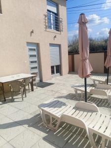 a patio with tables and a pink umbrella and chairs at Vila Komfor in Jajinci