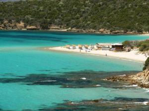 a beach with a group of people in the water at Casa Vacanze Capoterra in Capoterra