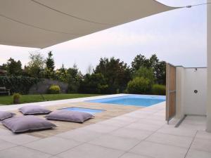 a swimming pool with pillows on a patio with an umbrella at Studia a apartmány U Karla in Turnov