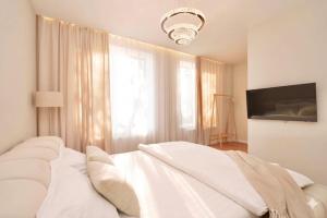 a white bedroom with a bed and a television at MONACO House in Chişinău
