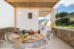 a patio with a table and chairs and a stone wall at Miles Away Residences in Platis Gialos