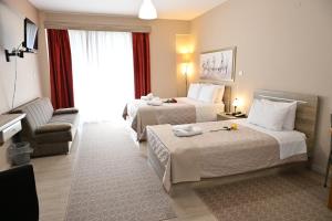 ein Hotelzimmer mit zwei Betten und einer Couch in der Unterkunft Hotel Vasilis Nafplio in Nafplio