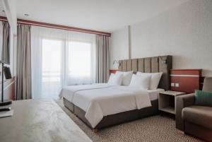 a hotel room with a large bed and a chair at OREA Resort Panorama Moravský kras in Blansko