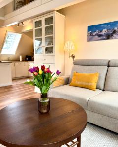 a living room with a couch and a table with flowers on it at Deichhof Whg 26 in Dunsum