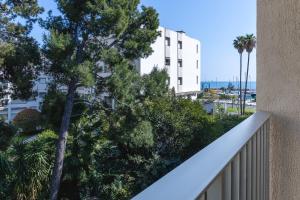 a balcony with trees and a white building at Super Menton Bord Mer in Menton