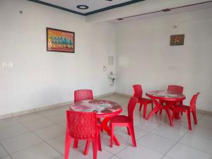 a group of red tables and chairs in a room at Keshav guest house in Rīngas