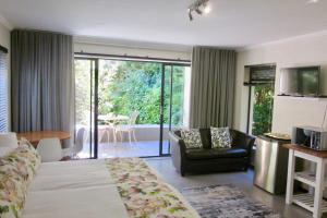 a hotel room with a bed and a living room at Pecan Tree Forest Studio B with Terrace in Stellenbosch