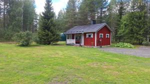 a red cabin in the middle of a grass field at Villa Lepola Sauna Suite in Rovaniemi