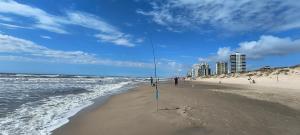 a person standing on a beach with a fishing pole at 203 Barra Refúgio in Tramandaí