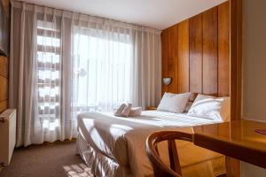 a bedroom with a bed with a desk and a window at Hotel Germania in Puerto Varas +86 photos