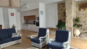 a living room with blue chairs and a stone wall at Casas de Correndelos in Ponte de Lima