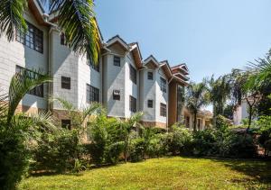 a large building with palm trees in front of it at Comfort Gardens in Nairobi