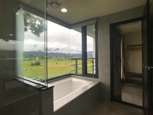 a bath tub in a room with a large window at 稻花香民宿 in Chishang
