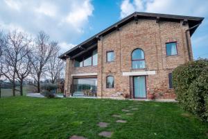 a brick house with a lawn in front of it at GuestHost - Casa delle Querce Villa with Pool in Gropparello