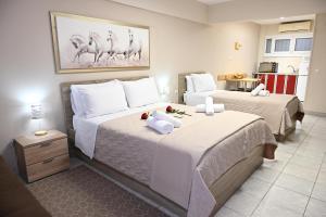 ein Hotelzimmer mit zwei Betten mit weißer Bettwäsche in der Unterkunft Hotel Vasilis Nafplio in Nafplio