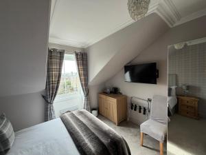 a bedroom with a bed and a tv on the wall at Grangeview Guest House in Edinburgh