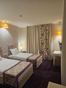 a hotel room with two beds and a window at Parish Hotel in Svilengrad