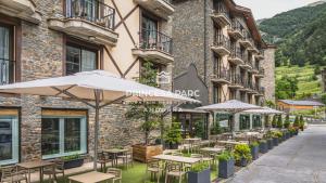 a row of tables and umbrellas in front of a building at Hotel Princesa Parc in Arinsal